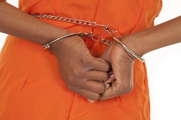 Person in jail jumpsuit with hands handcuffed behind the back
