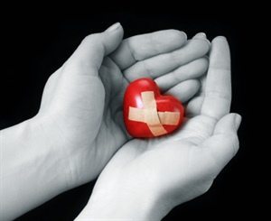 red heart with bandaid in palm of hands