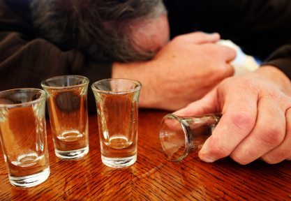 Man passed out on table with empty shot glasses