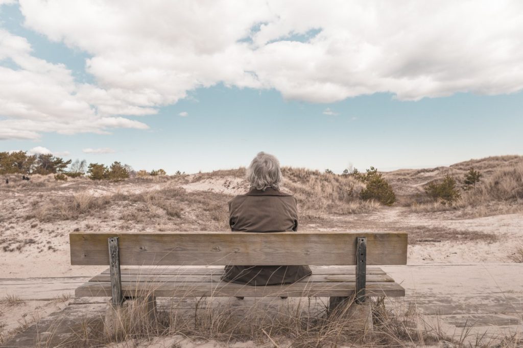 Senior person sitting on bench in sand dunes