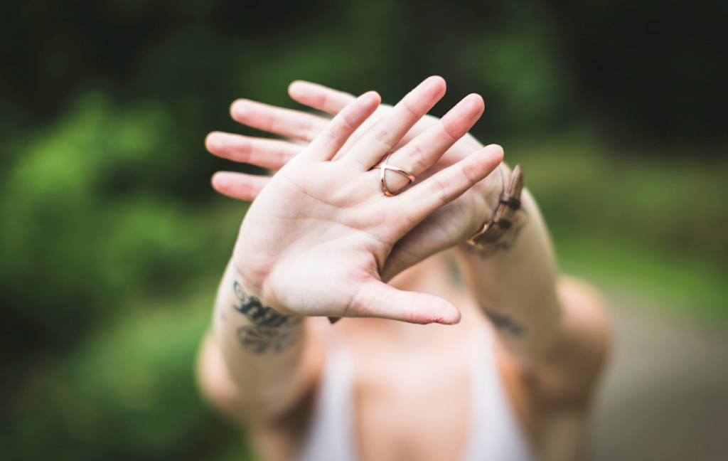 Woman's hands out covering her face