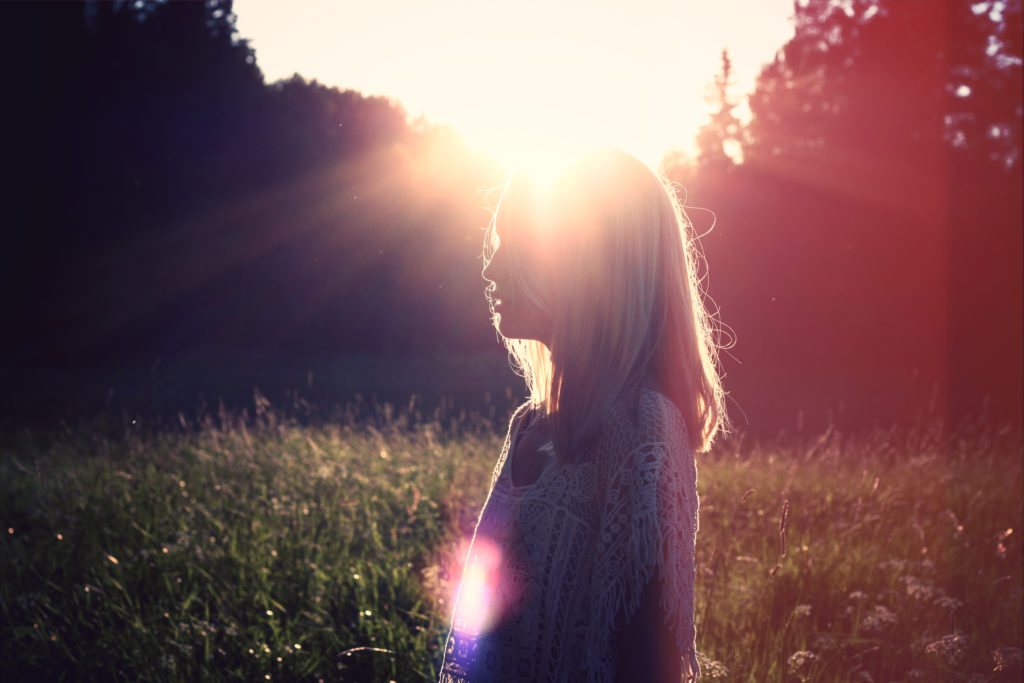 woman walking in field during sunset