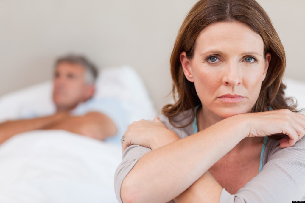 Sad woman with arms crossed and man behind her