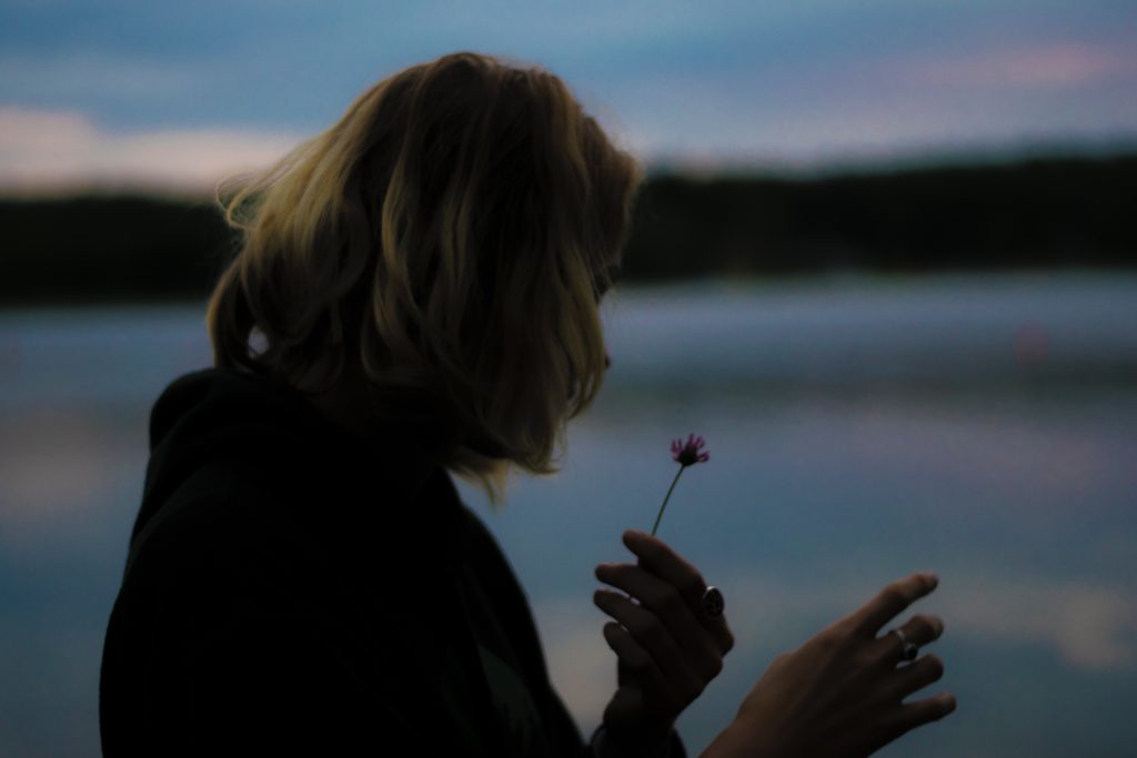 woman holding onto flower at dusk