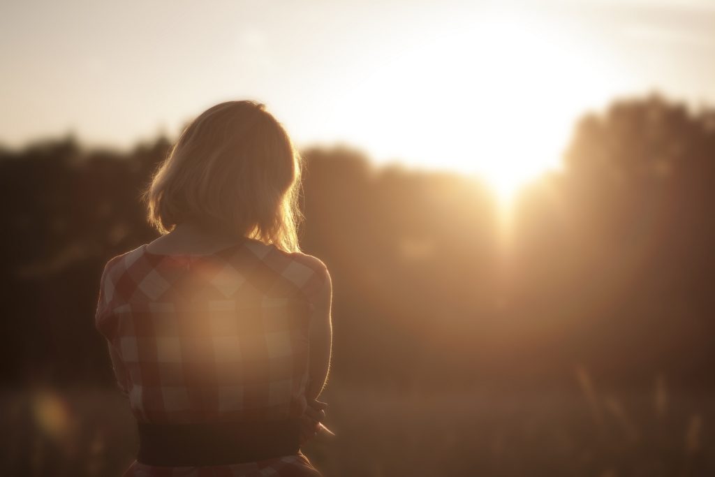 Woman standing in field during sunset