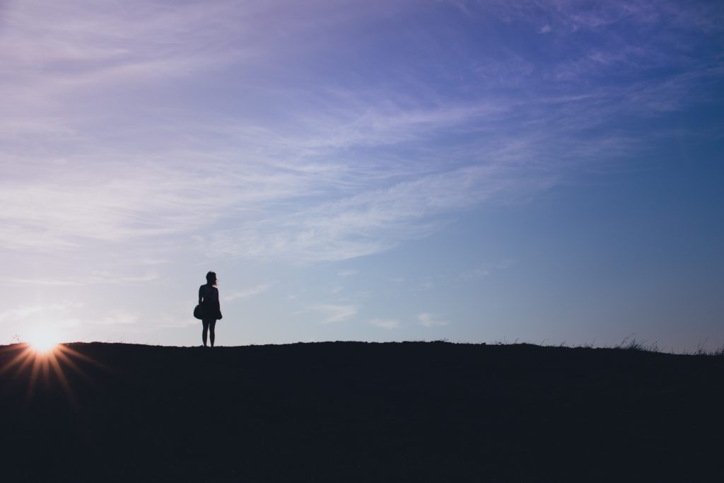 Silhouette of woman standing at the top of a hill
