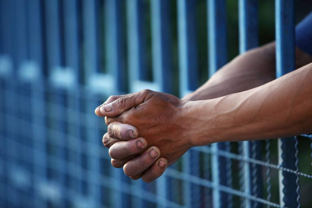 hands clasped prison bars