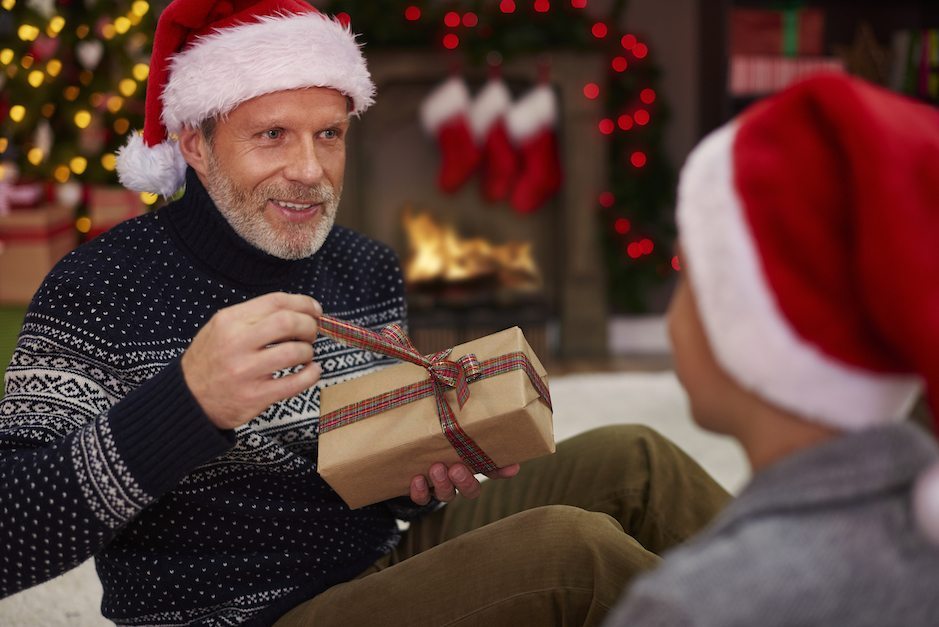 Father wearing Santa hat opening present