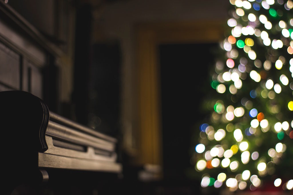 Piano and lit Christmas tree in the background