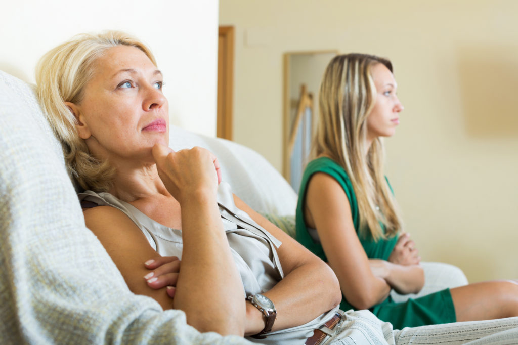 Mother and daughter sitting on couch upset