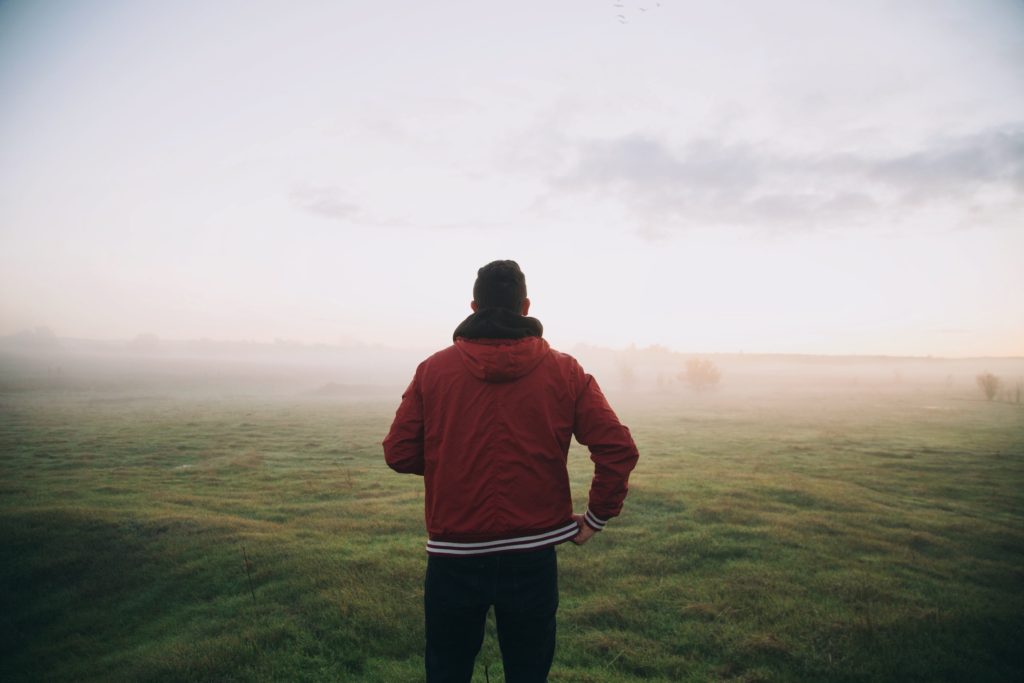 Man standing in a field on a foggy day