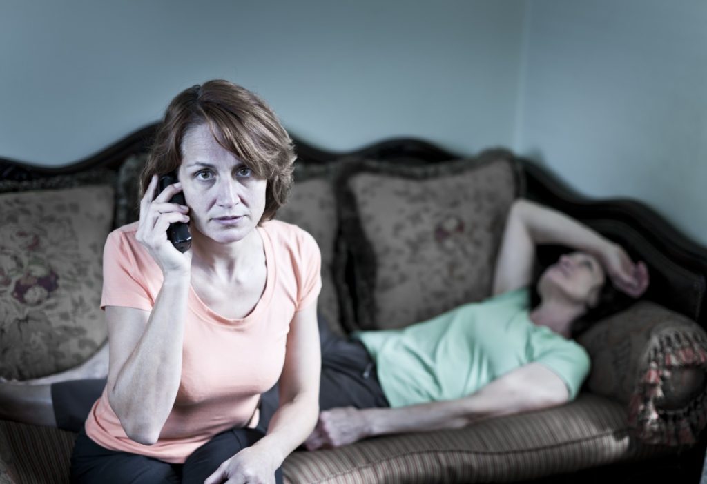 Woman on the phone with another woman lying on couch