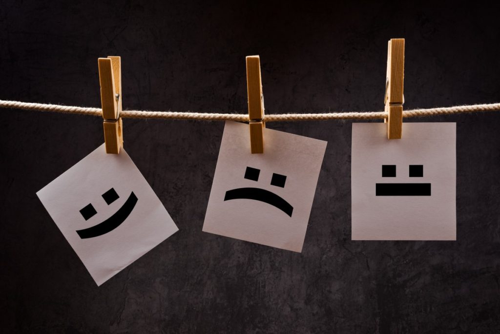 Pieces of paper with smiley face and upside down face pinned to a clothes line