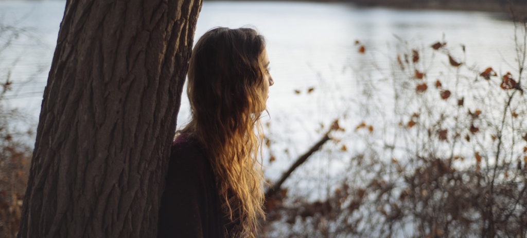 Girl leaning up against tree