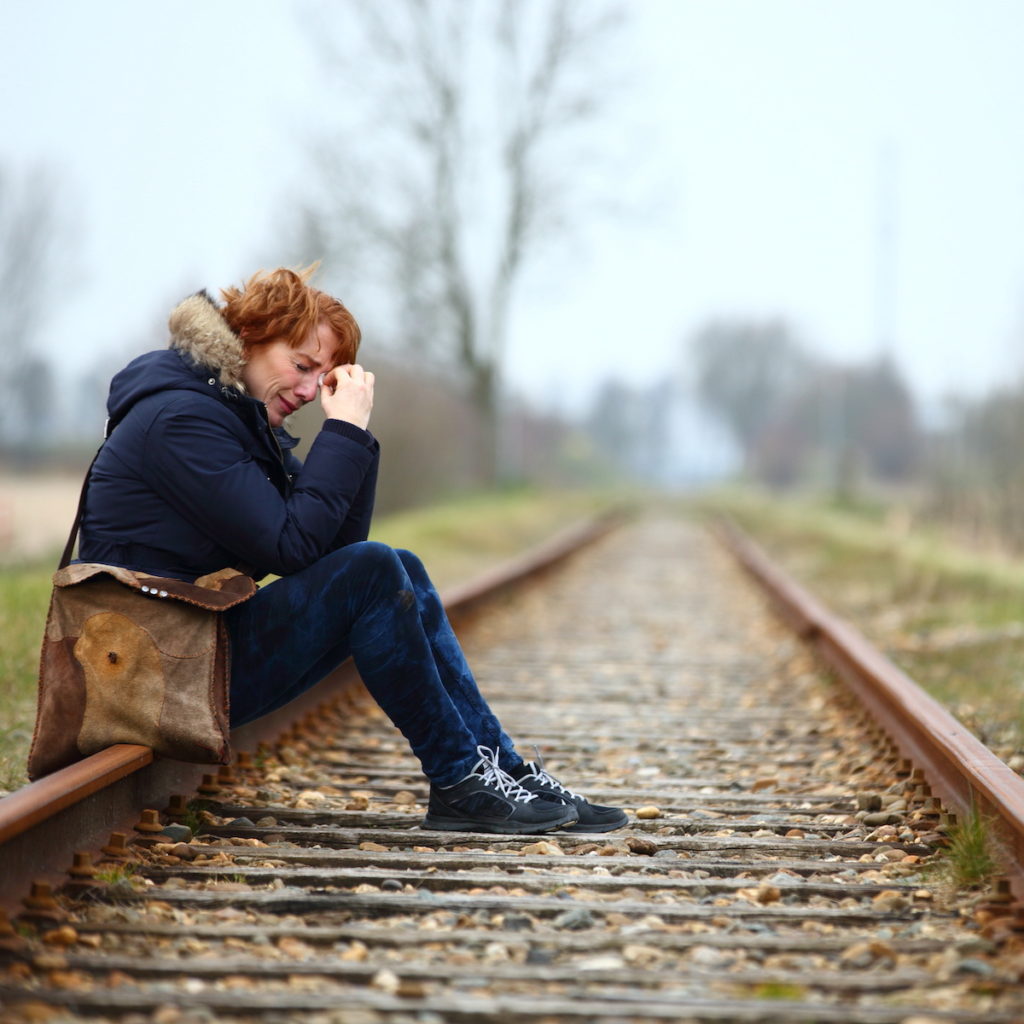 Crying woman sitting on railroad tracks