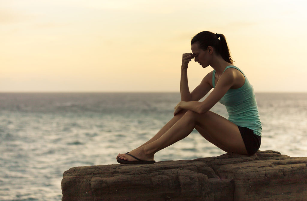 Woman sitting on rock by water