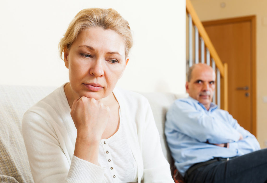 Woman resting chin on fist with man sitting behind her with crossed arms
