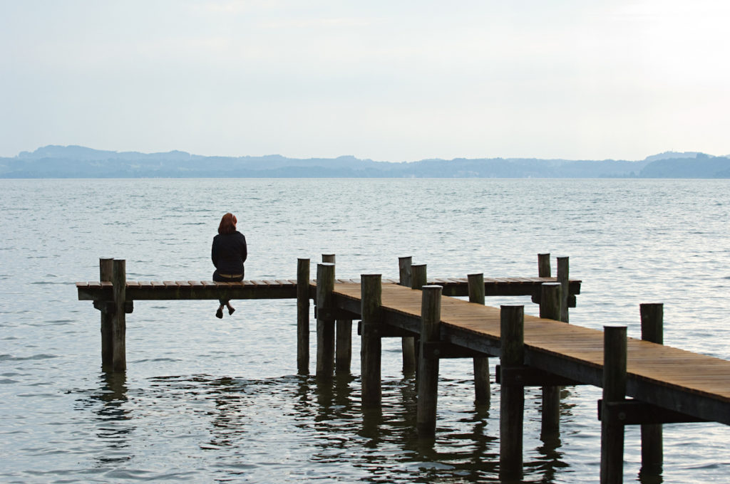 Woman sitting at the end of a pier