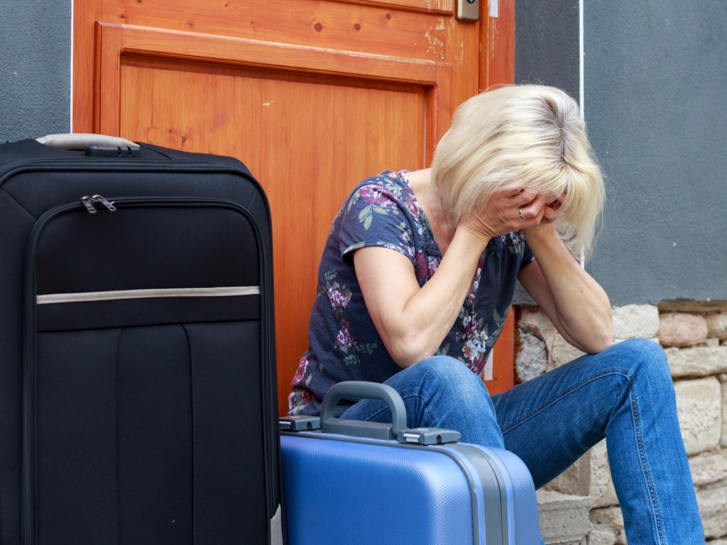 Woman sitting next to luggage with head in hands