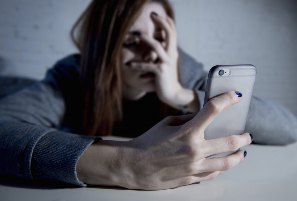 Woman holding phone with face in hand