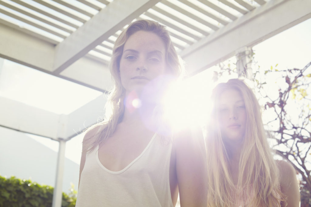 Two young women looking serious with sun shining behind them