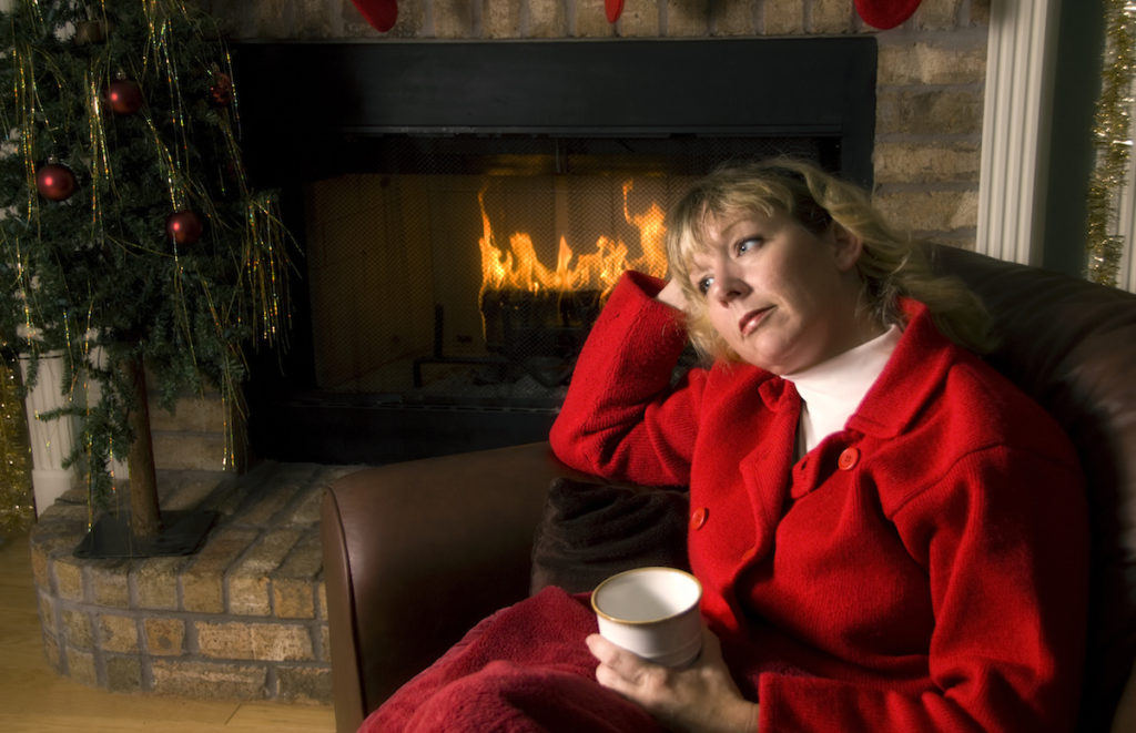 Sad woman sitting in front of a fireplace