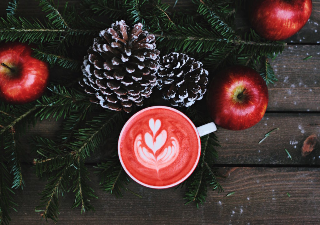 Mug with red coffee on table with apples and pinecones