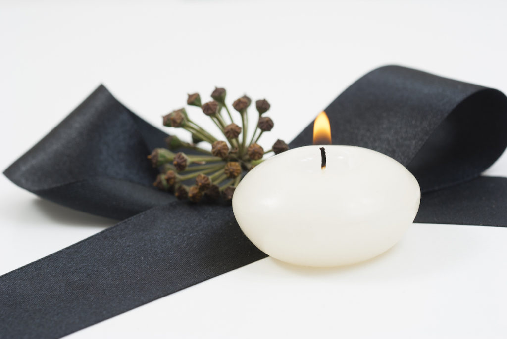 Lit candle next to black ribbon