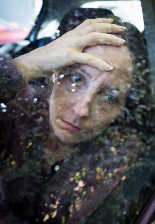 Distressed woman looking outside car window