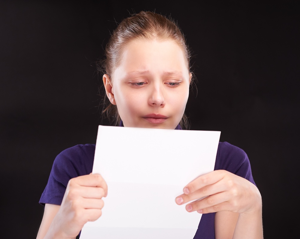 Young woman crying while reading a letter