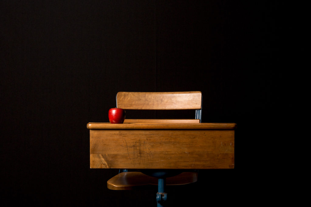 Apple sitting on wooden desk in dark room