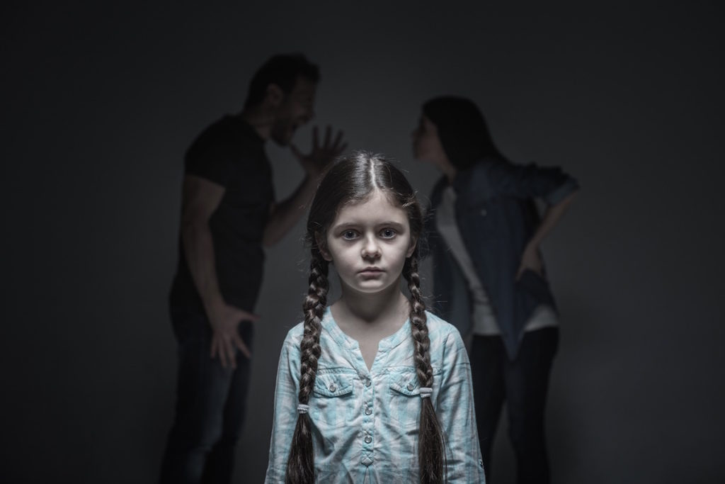 Daughter standing in front of arguing parents