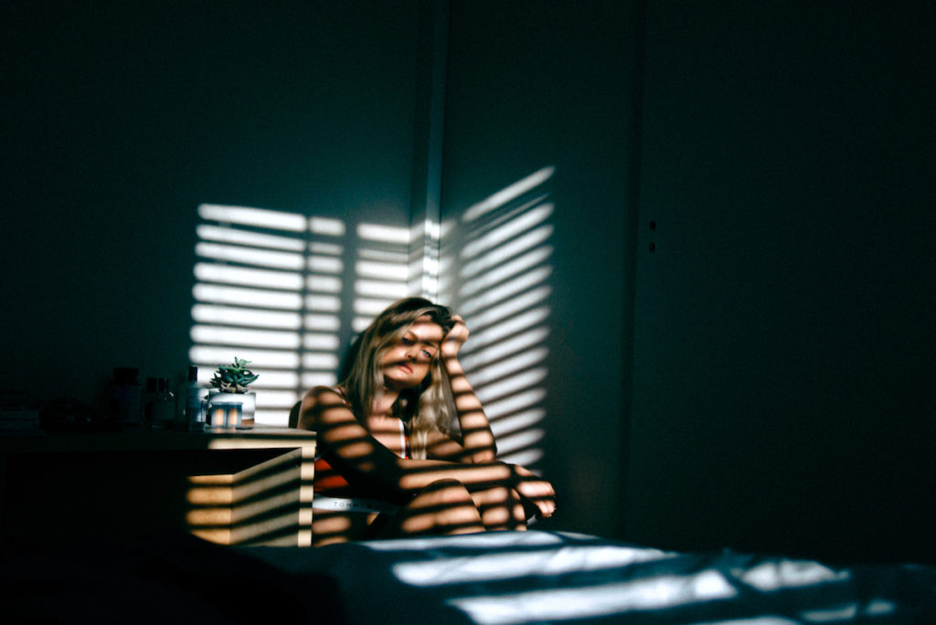 Young woman sitting in corner of dark room