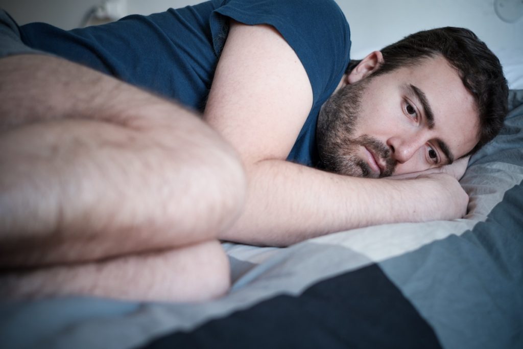 Sad man curled in bed