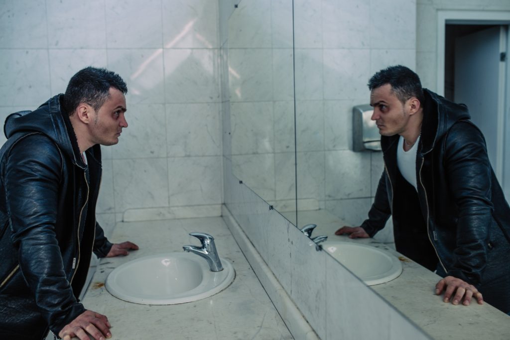 Angry man looking at himself in the mirror