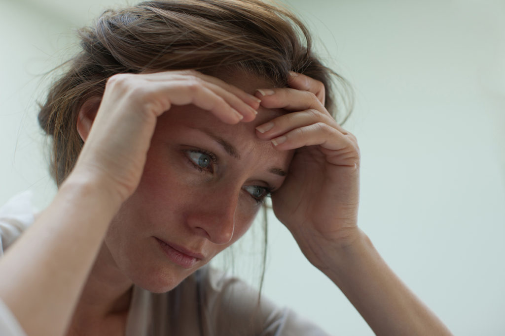 Woman's hands on forehead looking stressed