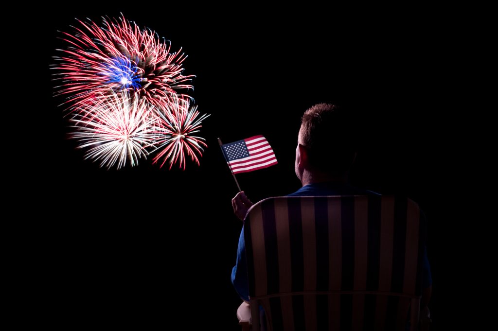 Man waving American flag during fireworks show