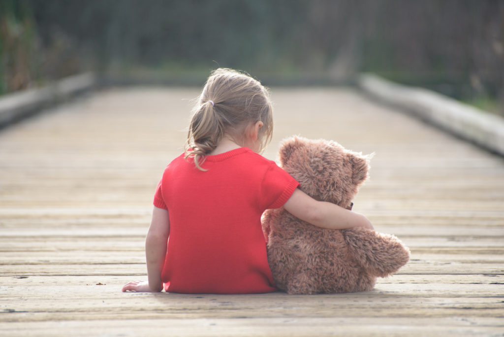 Young girl with arm around teddy bear