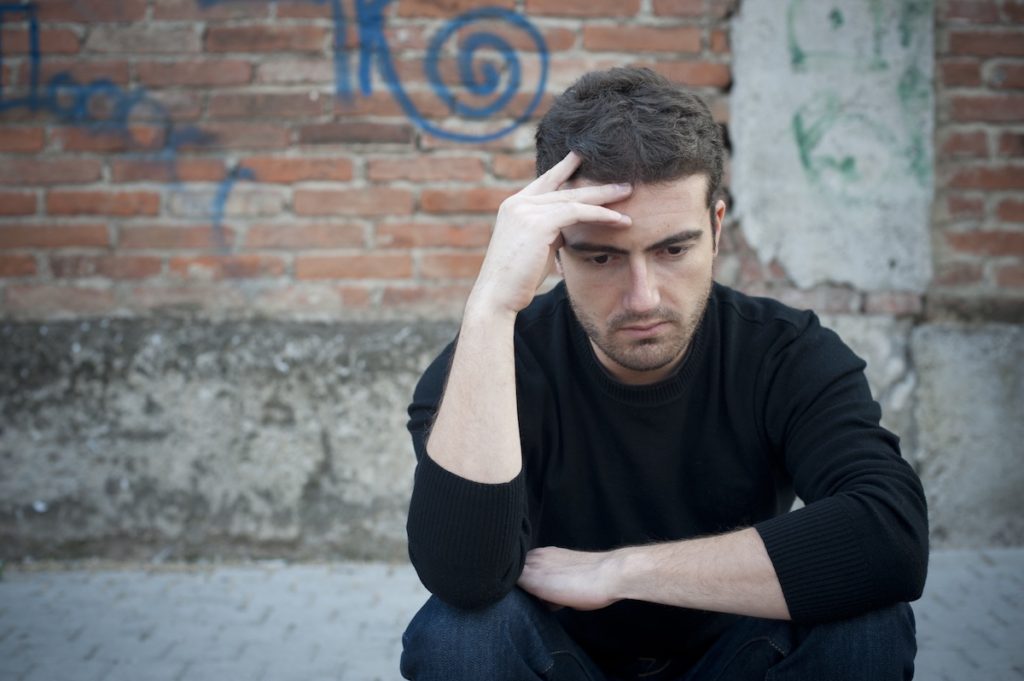 Sad man sitting looking down at the ground
