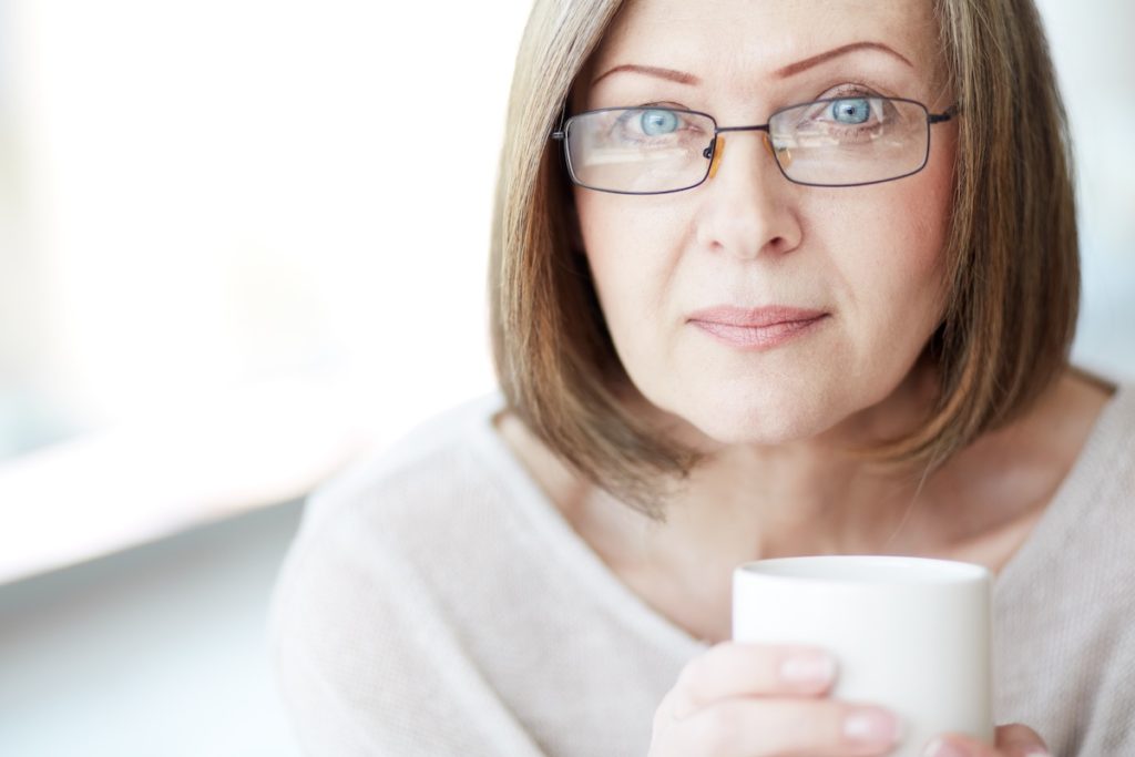 Woman wearing glasses holding coffee cup