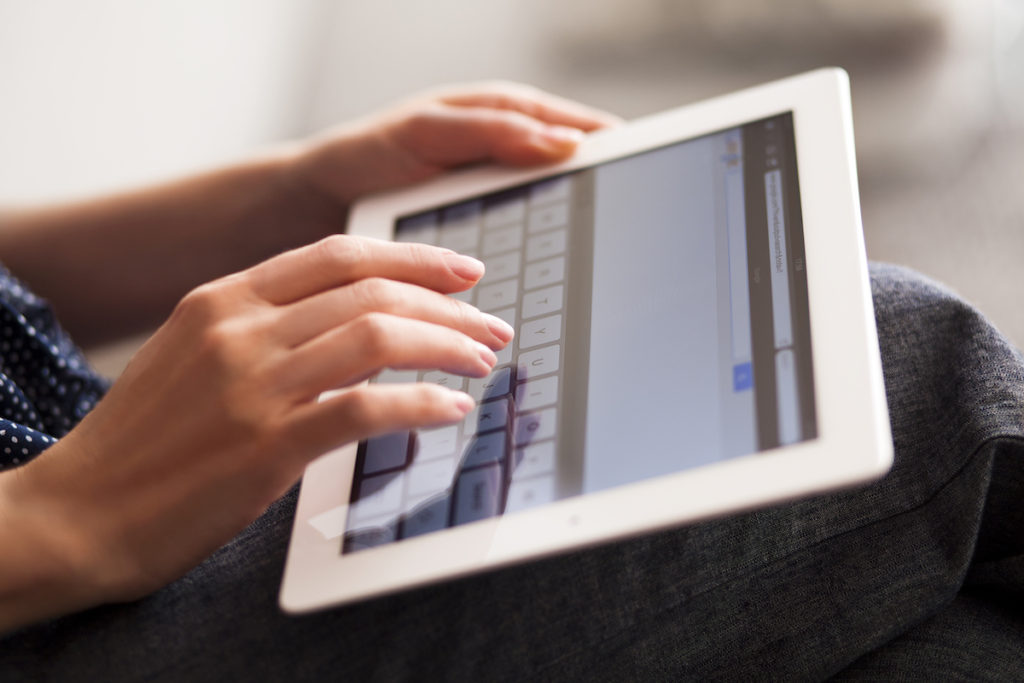 Woman's hands typing on tablet