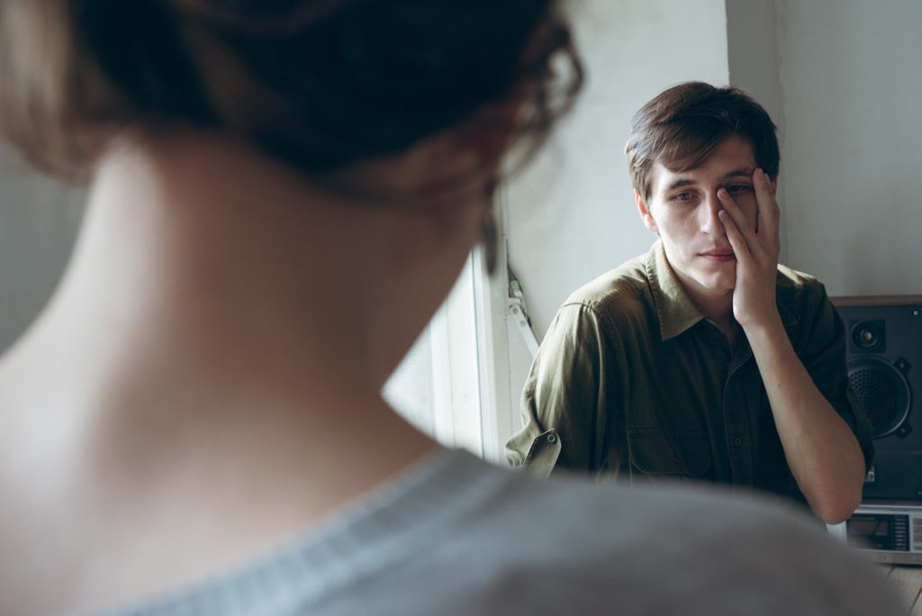 The back of a woman talking to a sad young man