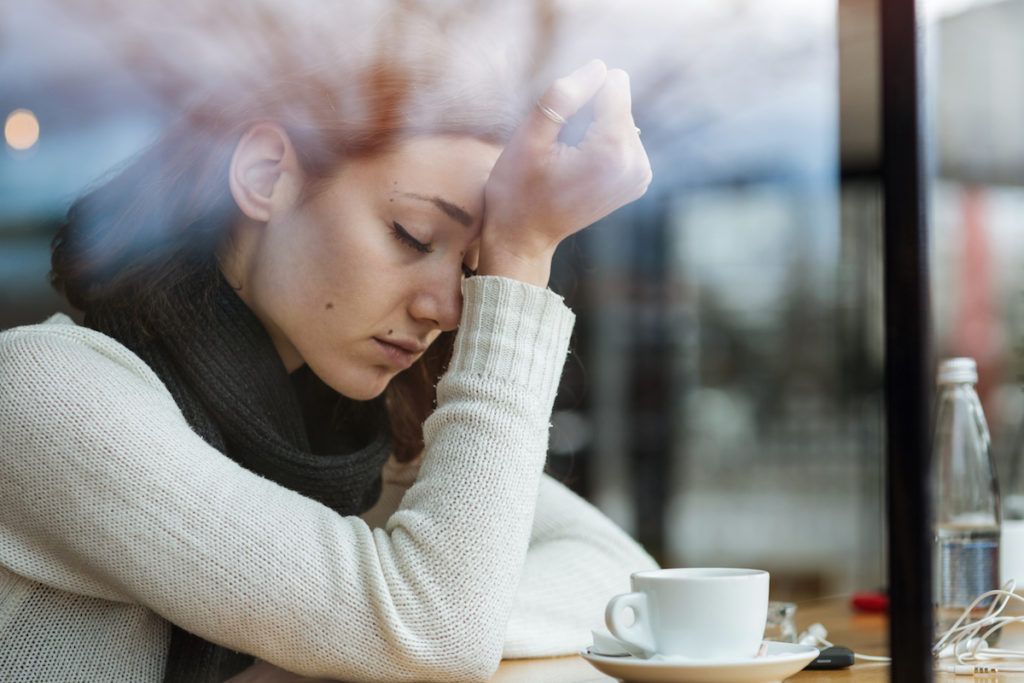 Woman with eyes closed sitting in a coffee shop
