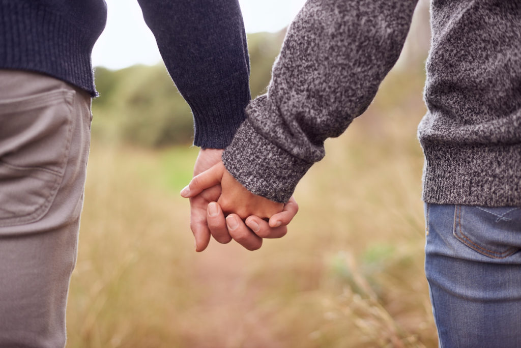 Man and woman holding hands walking through a field