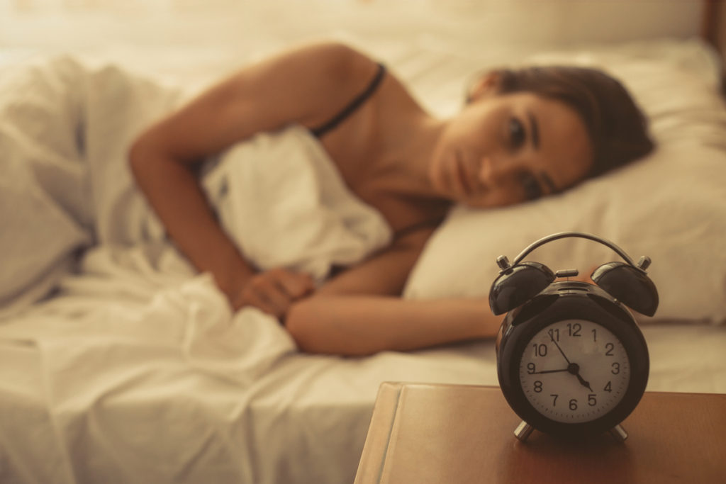 Woman in bed staring a clock