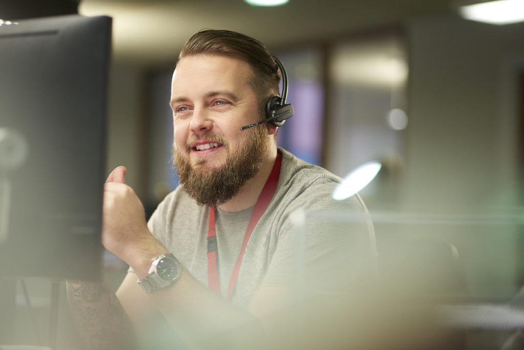 Man with headset sitting in front of computer screen