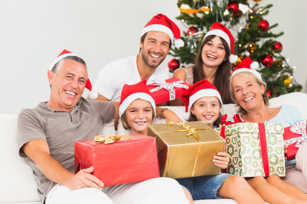 Family wearing santa hats and holding presents