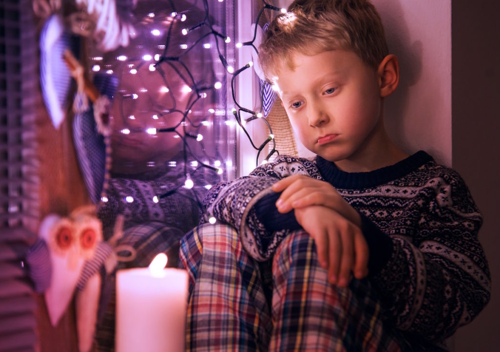 Sad kid sitting around Christmas lights