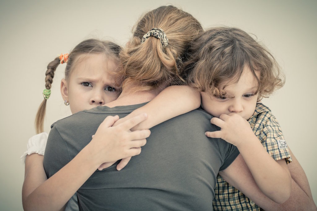 Mom hugging two young children