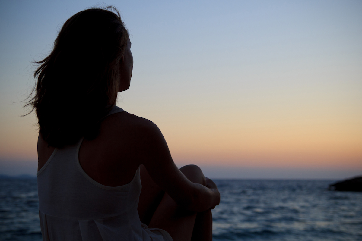 Woman sitting and looking out at ocean